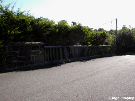 Looking along a road with a bridge rail alongside it