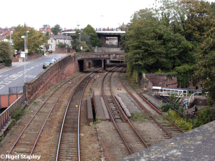 Picture of a road alongside a railway line, with a canal going underneath