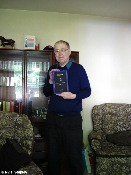 Photo of a man holding up a paperback book