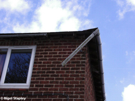 Photo of broken guttering hanging off the corner of a house