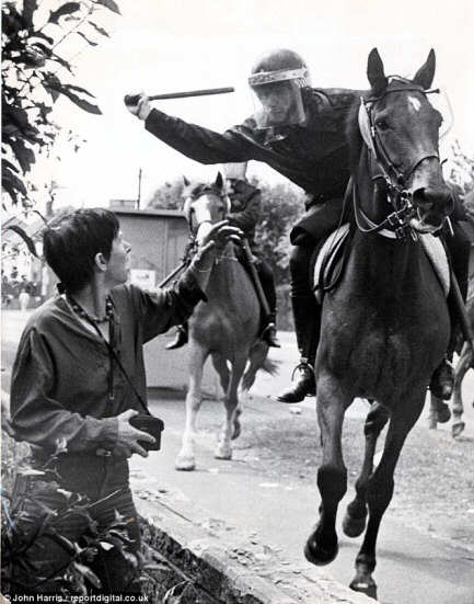 Photo of a cop on horseback about to strike an unarmed photographer with a truncheon