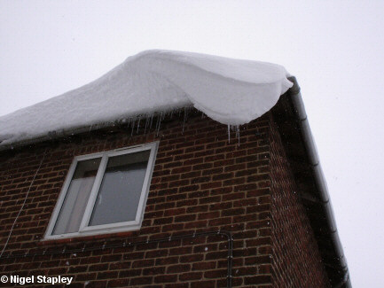 Picture of frozen snow overhanging the corner of a house roof