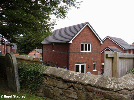 Photo of some new houses taken over a stone wall